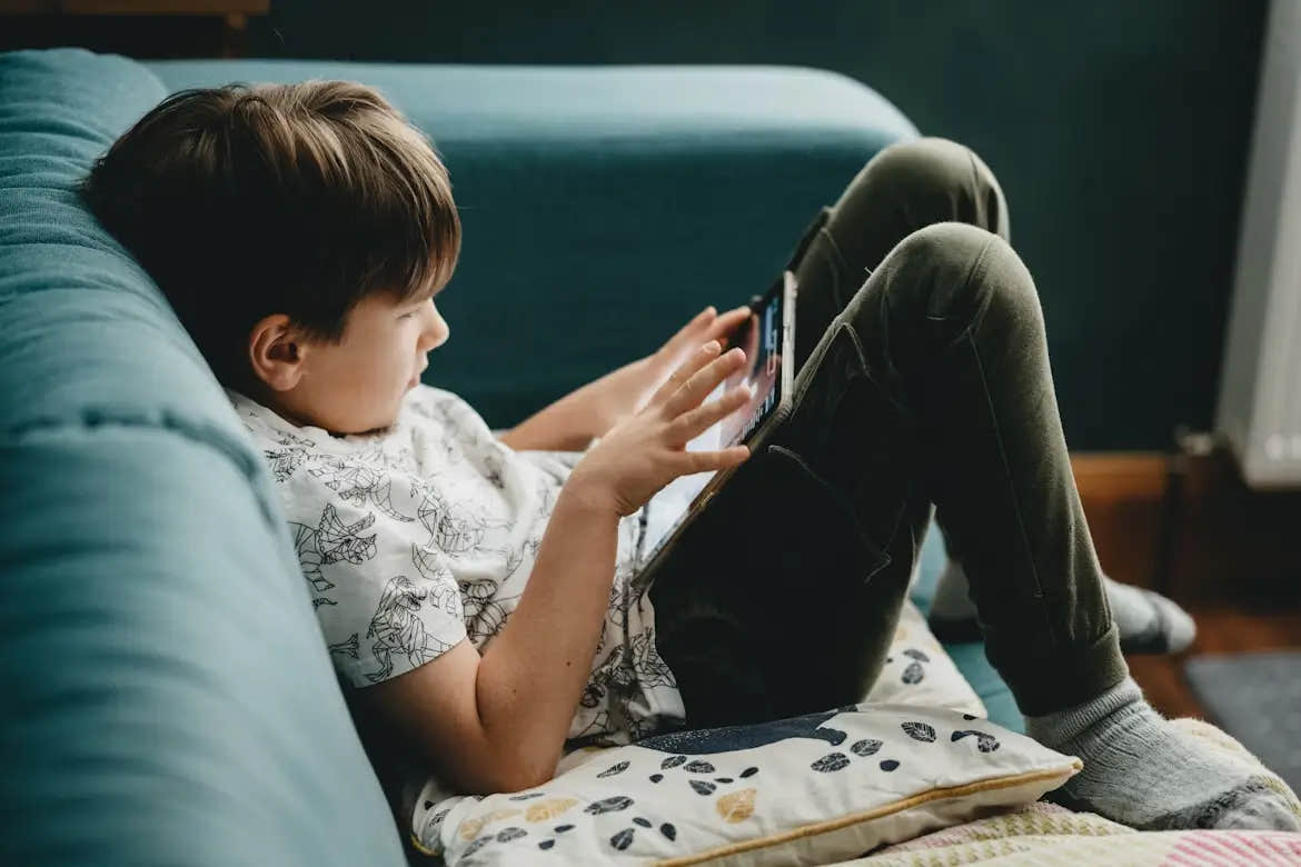 Child with ADHD lying on couch using a tablet.