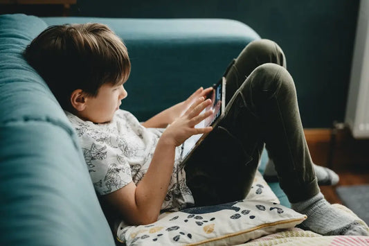 Child with ADHD lying on couch using a tablet.