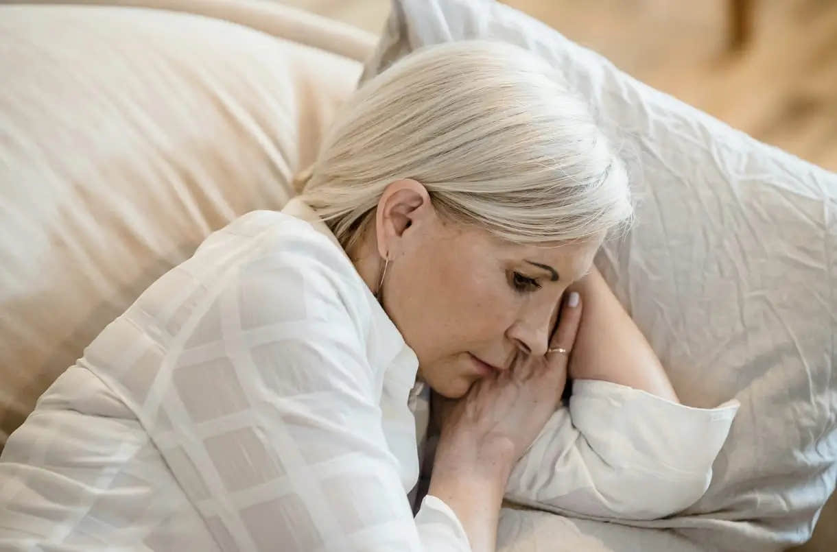  Woman lying on her side in bed, resting on a pillow.