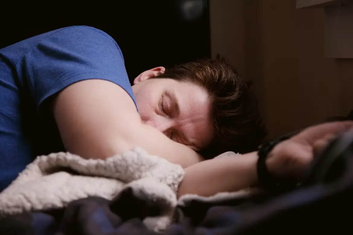 Person sleeping on their side in a dim room.