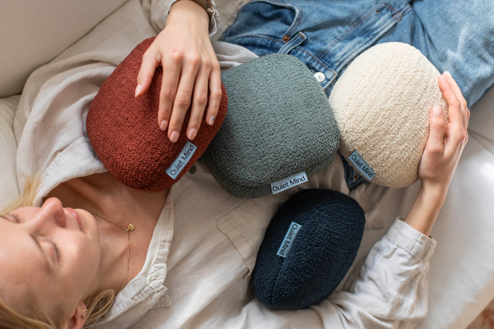 One Quiet Mind weighted pillows in soft colors arranged across a relaxed couch moment.
