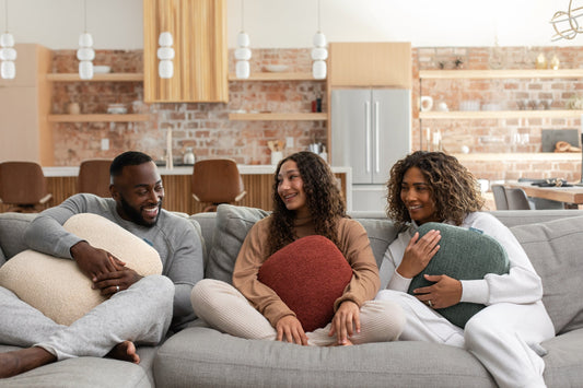 Three people holding Quiet Mind weighted pillows while relaxing together on a sofa.