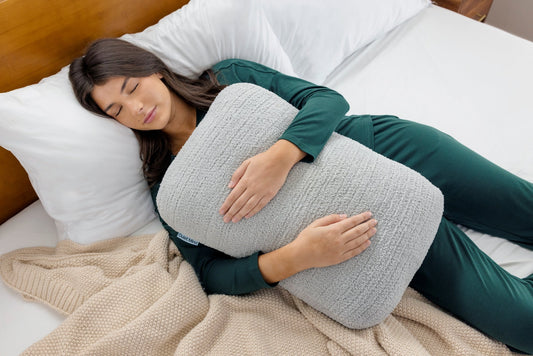 One Quiet Mind weighted body pillow hugged in bed for gentle, cozy sleep support.