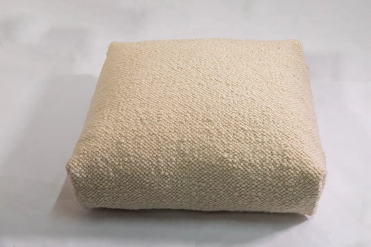 A soft, textured weighted pillow in a neutral beige tone, designed for calming deep pressure support.