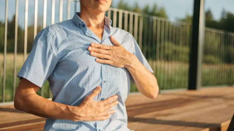 Man holding chest and belly, focusing on heartbeat and breath.