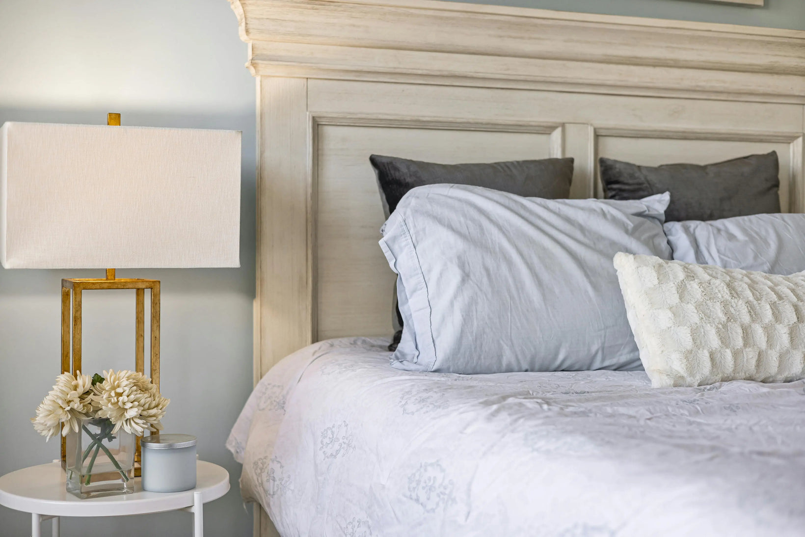 Soft white and grey weighted pillows arranged neatly on a cozy, light-toned bed.