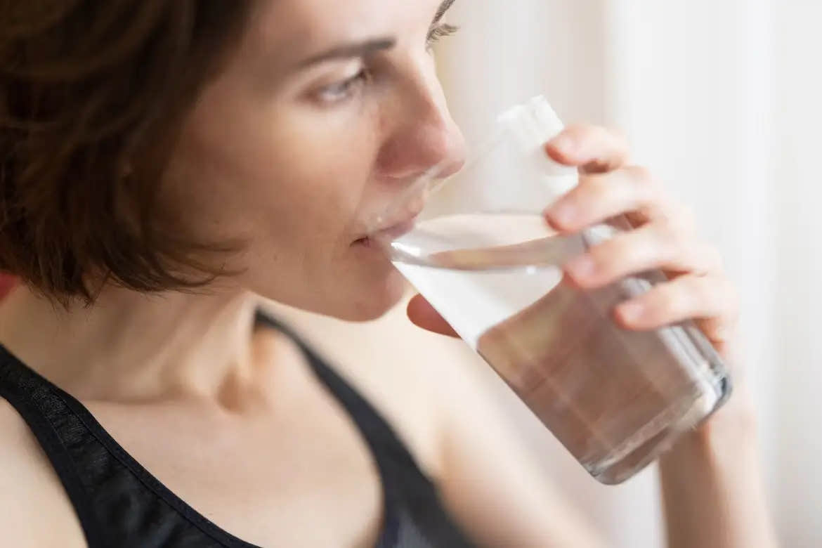Woman drinking a glass of water to sooth her anxiety.