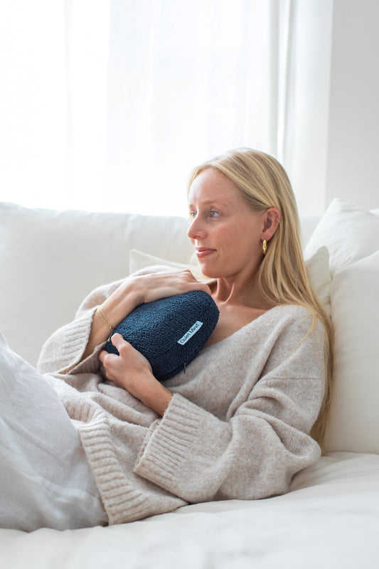 Woman holding a navy Quiet Mind weighted pillow while relaxing in bed.