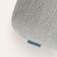 Close-up of a light gray textured plush cushion with a small blue tag reading 'Quiet Mind' on a white background.